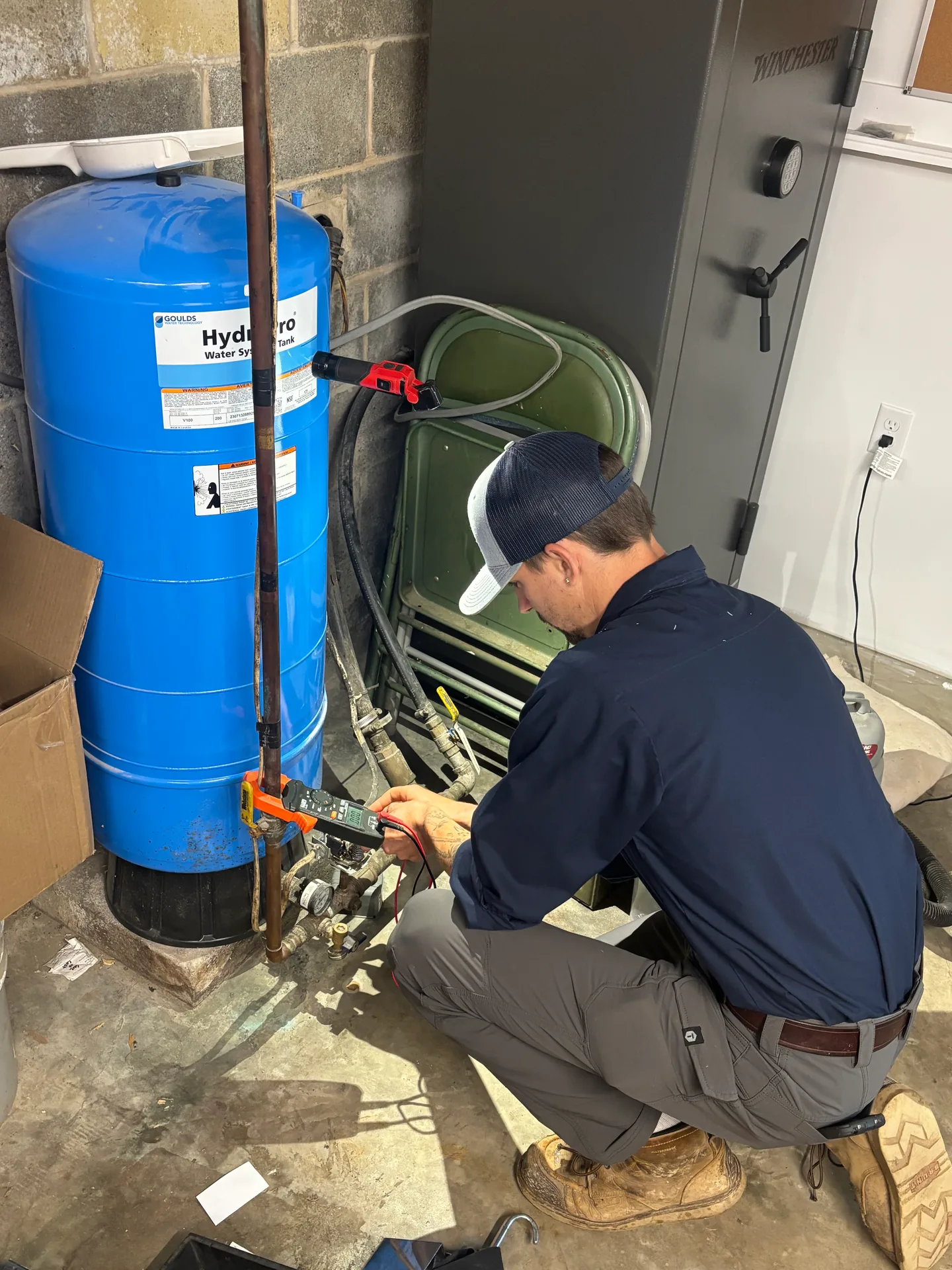 Pressure Tank Valve Repair Knauss Plumbing owner repairing valves and piping beside a blue pressure tank.