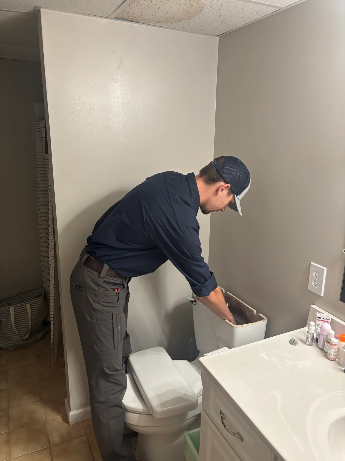 Knauss Plumbing owner preparing a bathroom toilet area during a repair or installation.