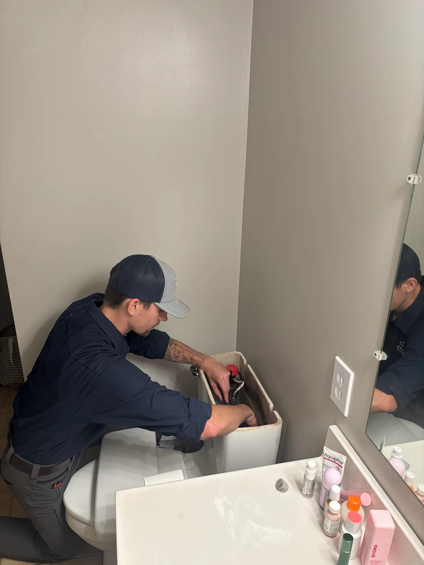 Knauss Plumbing owner repairing a toilet tank in a residential bathroom.